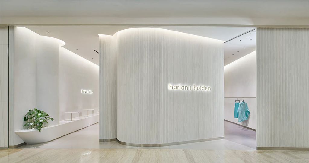 Harlan+Holden interior with curved white walls and illuminated branding